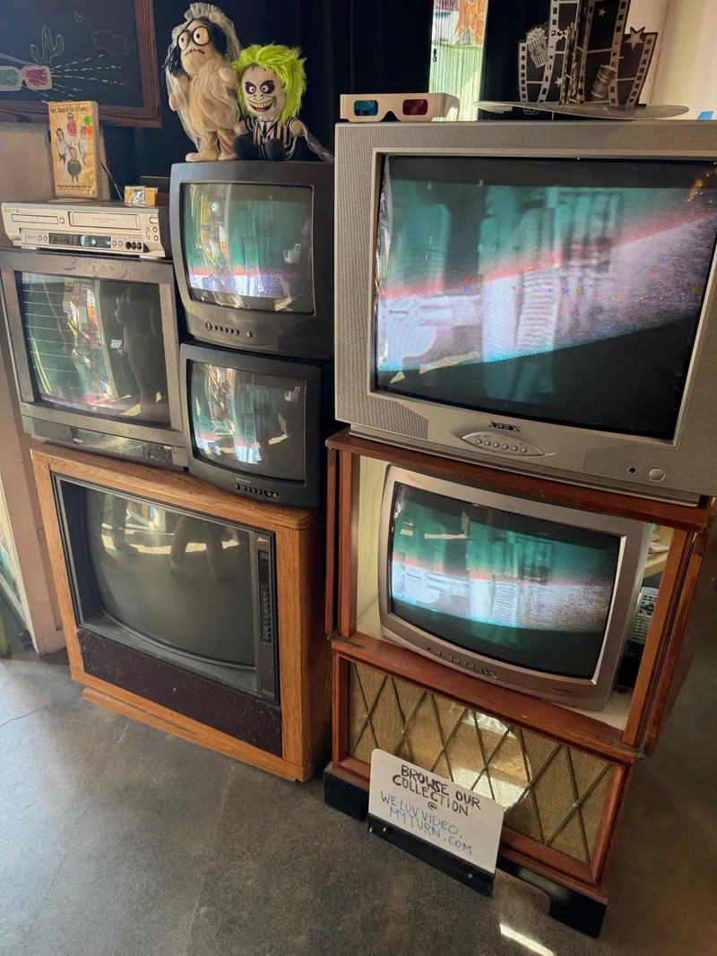 A collection of vintage televisions and electronics, including a VCR and a retro radio cabinet.
