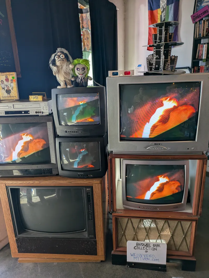 A collection of vintage televisions and media players, some displaying abstract fiery images.