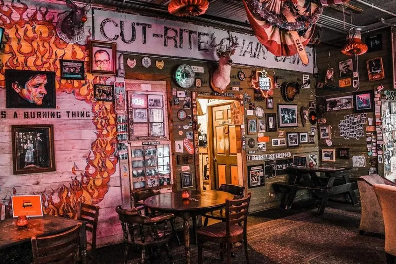 The interior of Mean Eyed Cat Bar with rustic walls covered in photos, memorabilia, and flame artwork.