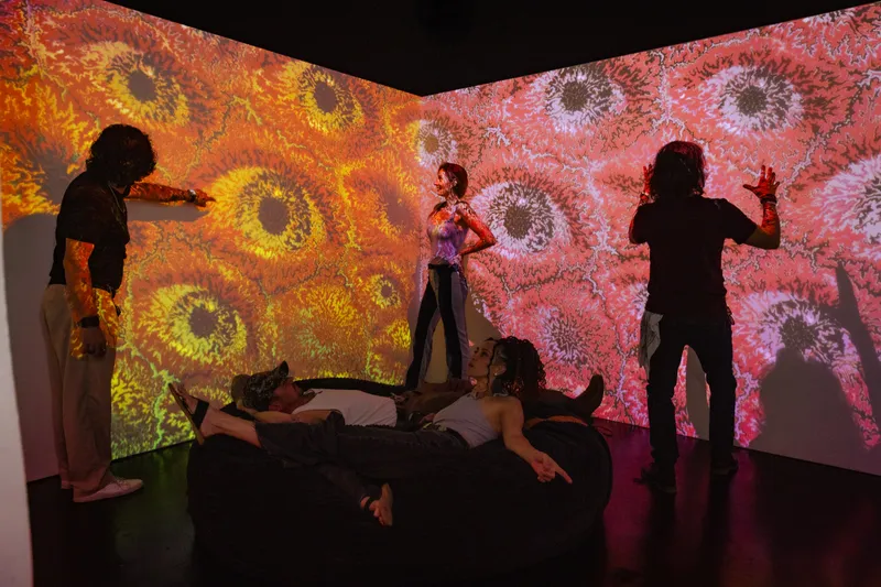 People interacting with a large-scale, colorful, abstract art installation projected onto walls.