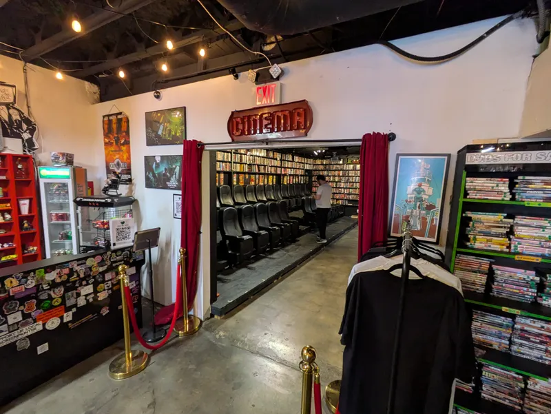 Interior of a cinema with rows of seats and shelves of DVDs for sale.