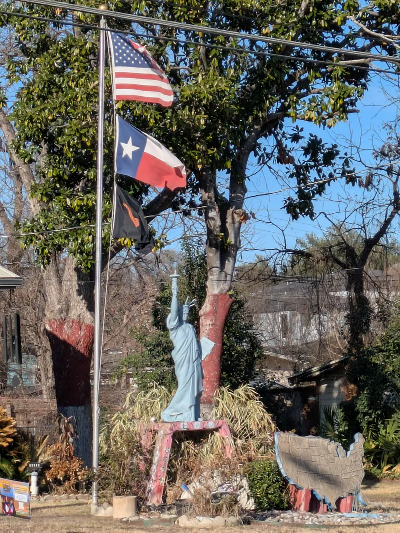 Statue of Liberty replica with American and Texas flags flying above.