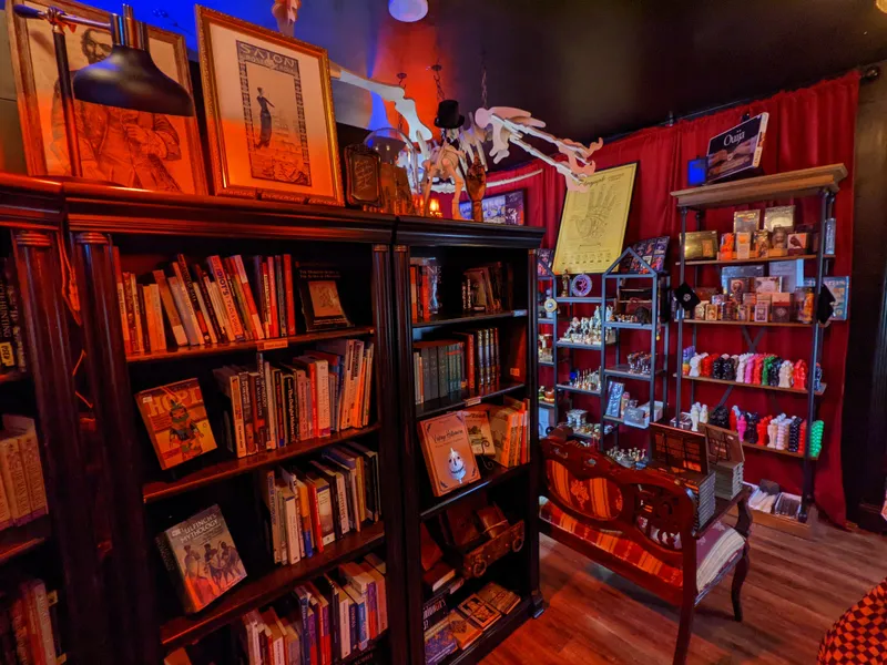 A dimly lit room showcases shelves filled with books, curios, and anatomical models. A Ouija board box sits on a top shelf.