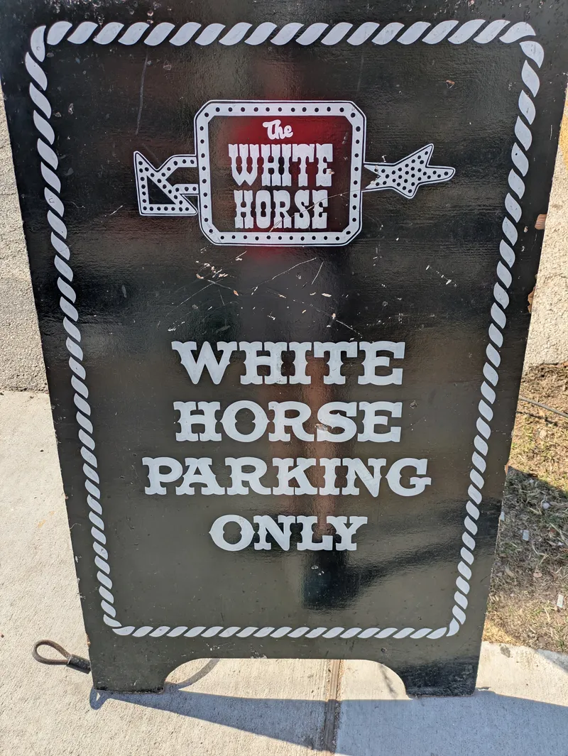 A black A-frame sign with white lettering indicating "The White Horse Parking Only".