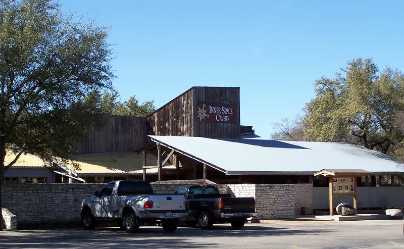The Inner Space Cavern building with a sign and two trucks parked outside.
