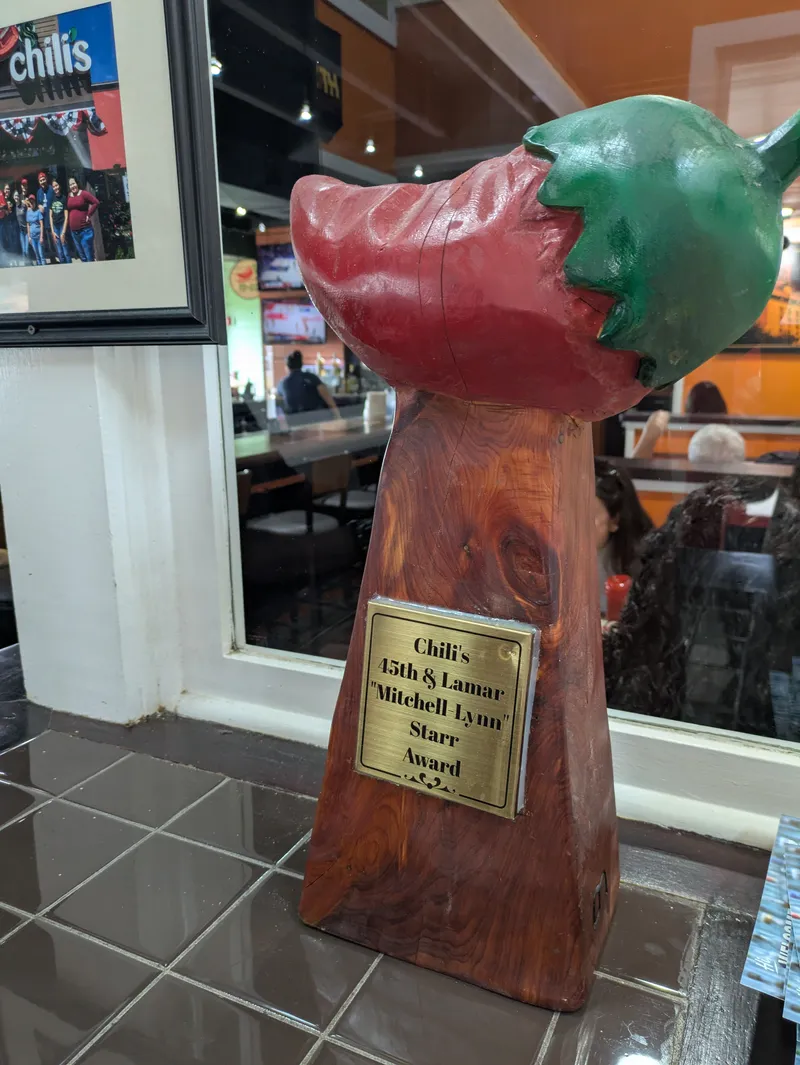A wooden trophy shaped like a chili pepper with a plaque that reads "Chili's 45th & Lamar Mitchell Lynn Starr Award".