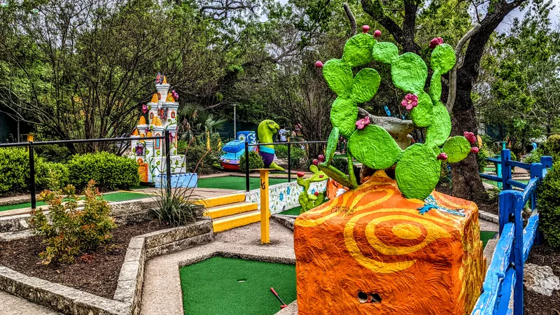 A whimsical miniature golf course with colorful, cartoonish obstacles like a castle and a cactus.