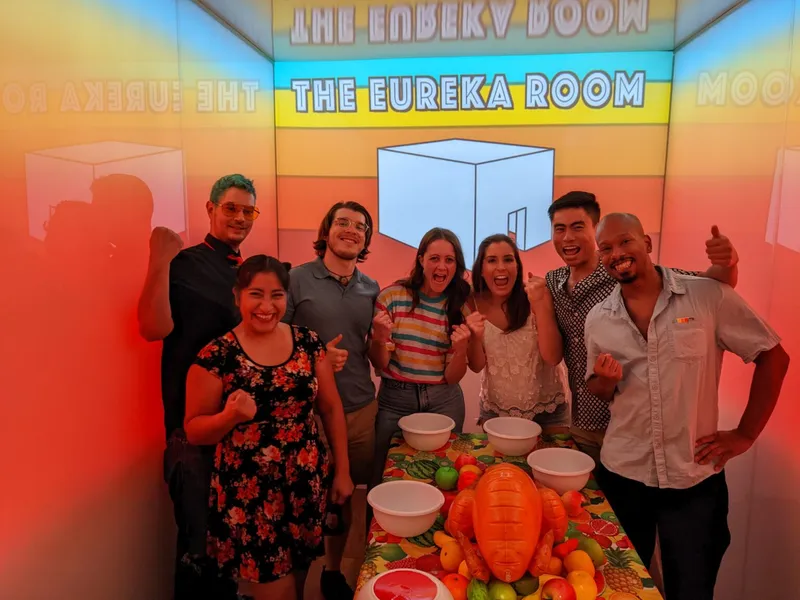 A group of friends celebrating in "The Eureka Room" with a table full of fruit and bowls.