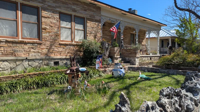 A house with a stone facade and a porch decorated with garden gnomes and a snowman.
